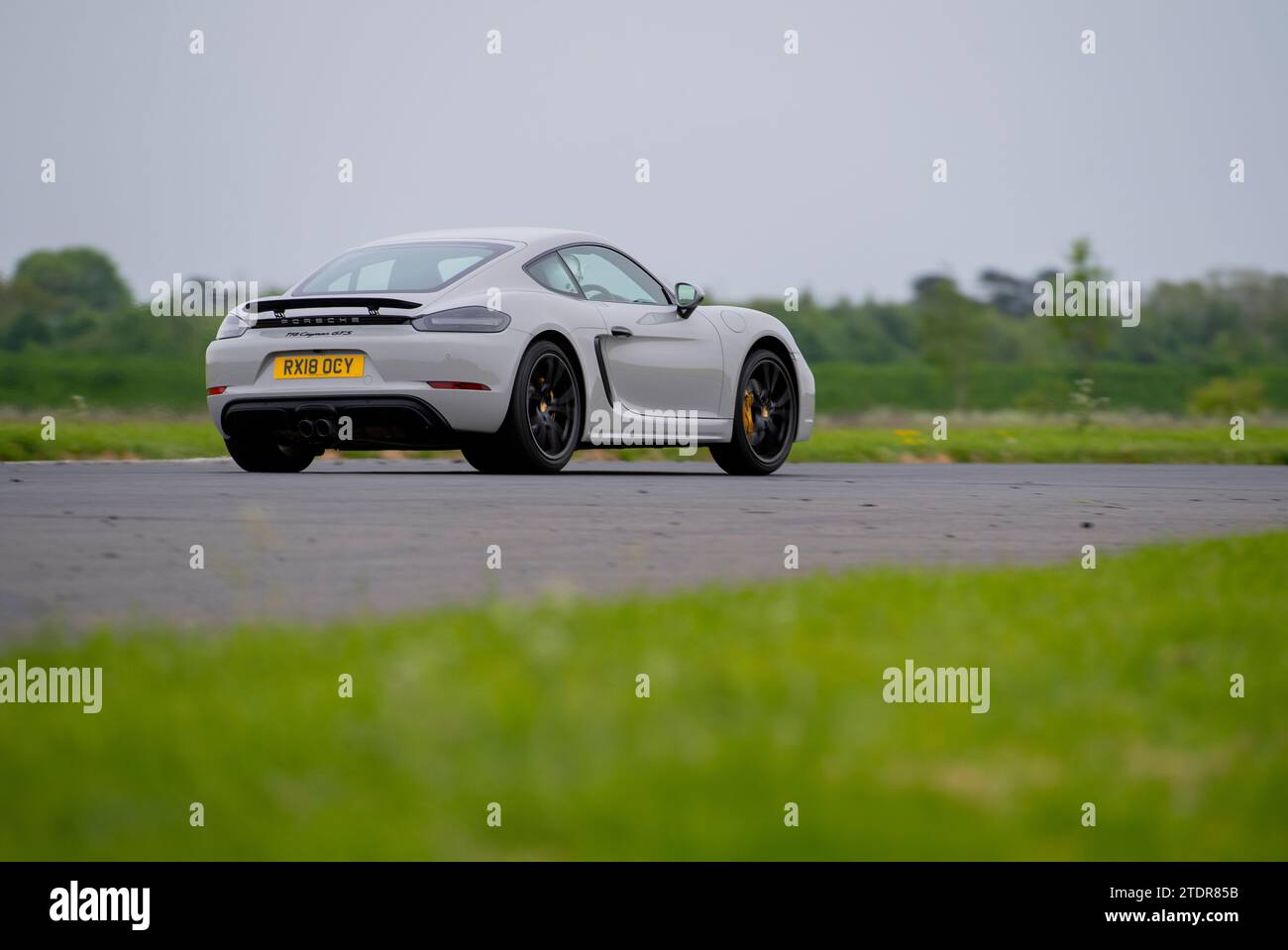 Porsche Cayman conduisant rapidement sur piste lors d'une course de jour Banque D'Images