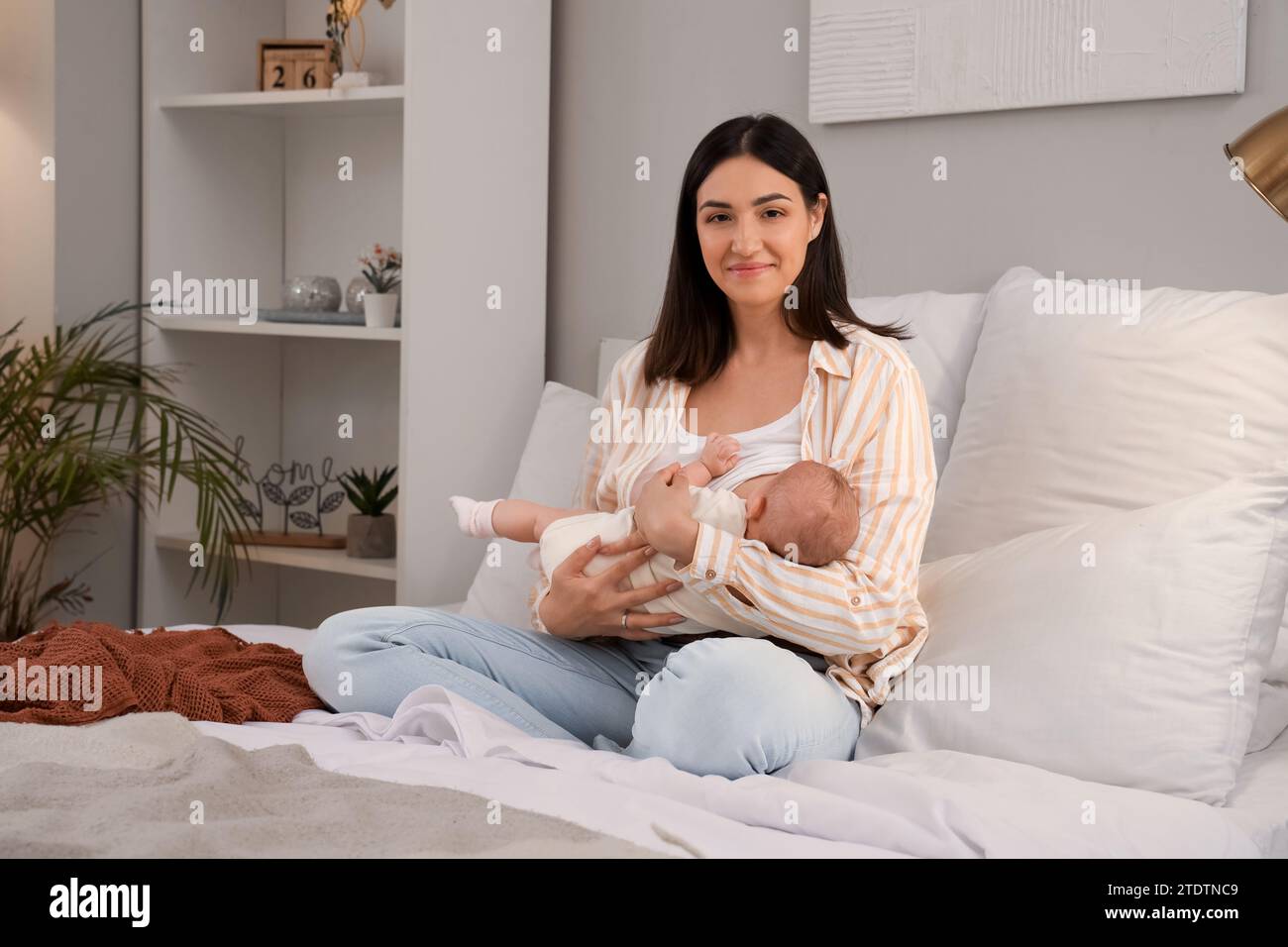 Jeune femme allaitant son bébé dans la chambre Banque D'Images