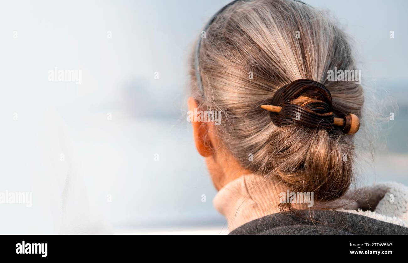 Une femme âgée avec des cheveux gris argentés, attachée avec une épingle à cheveux. Banque D'Images