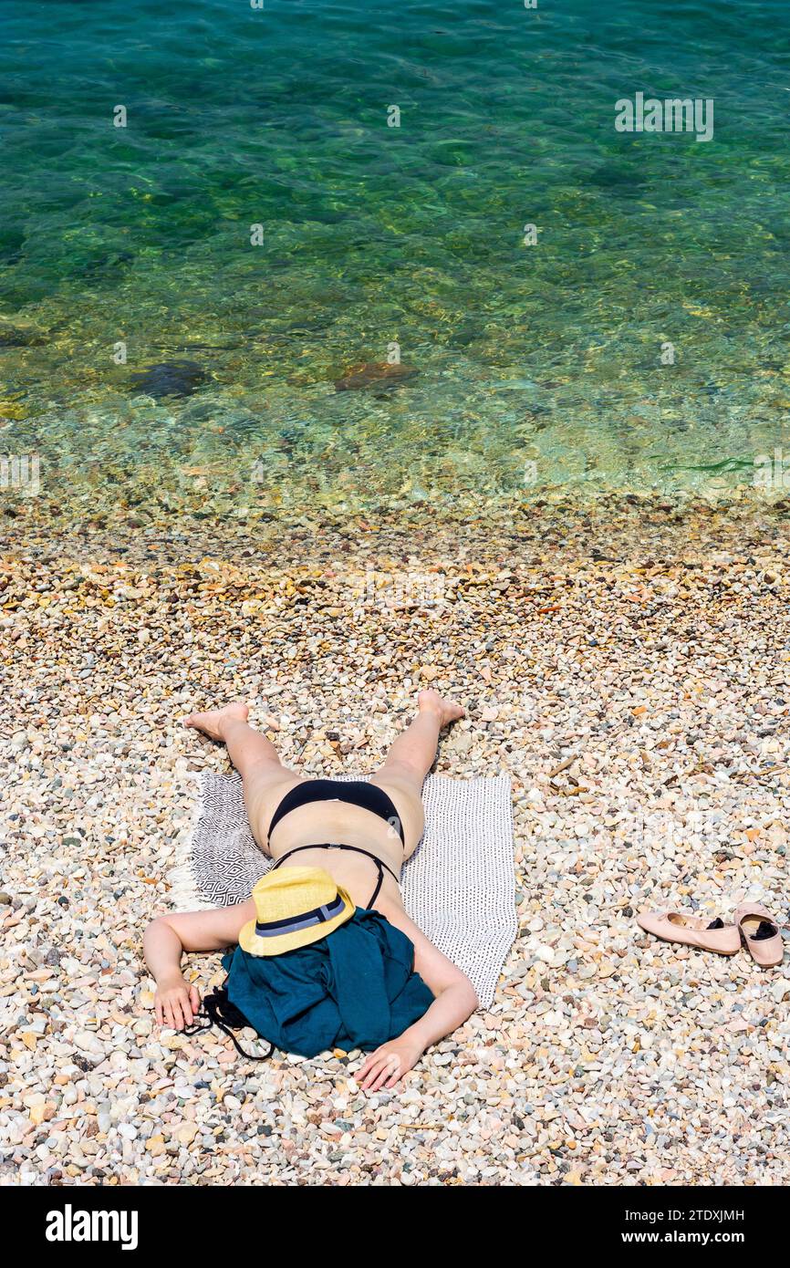 Torri del Benaco : Femme couchée face cachée sur la plage, chapeau de soleil, bikini, Lago di Garda (Lac de Garde) à Vérone, Vénétie, Italie Banque D'Images