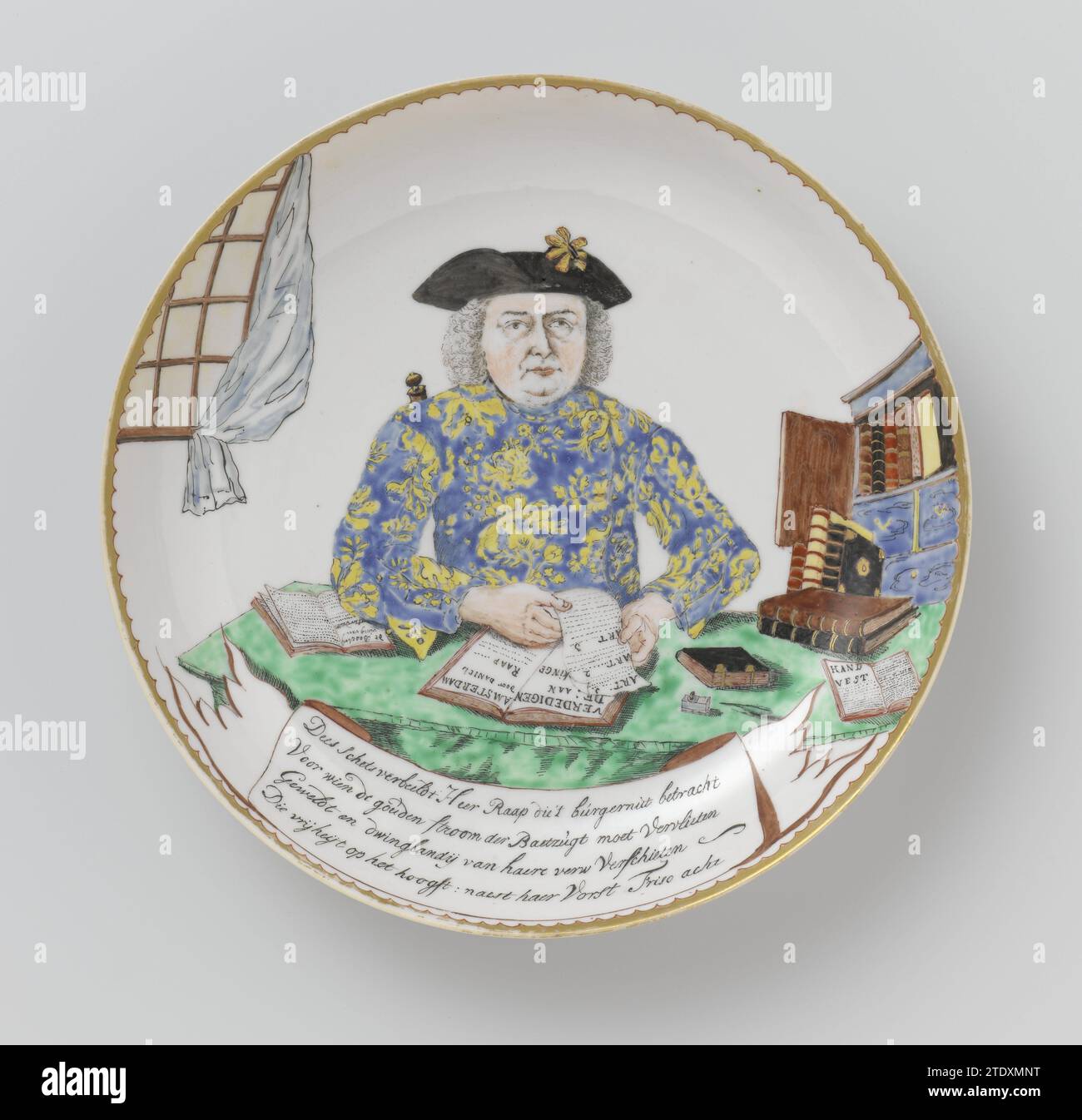 Soucoupe-plat avec un Portrait ou Daniel Raap, Pleun Pira, 1750 plat en porcelaine, peint sur le glaçage en bleu, rouge, vert, jaune, brun, noir et or. Sur le devant un portrait d'un homme, Daniel Raap, marchand de porcelaine d'Amsterdam, assis à une table sur laquelle des livres et des fournitures d'écriture, à droite une armoire bleue dans laquelle des livres, une fenêtre avec rideau blanc à gauche; devant la table, une banderole avec l'inscription : 'esquisse de Dees représente M. Raap qui a exercé / pour qui le ruisseau d'or de la gloire de baet doit blanchir / violent et Dwinglandij van Hare Fiddled / qui libère Banque D'Images