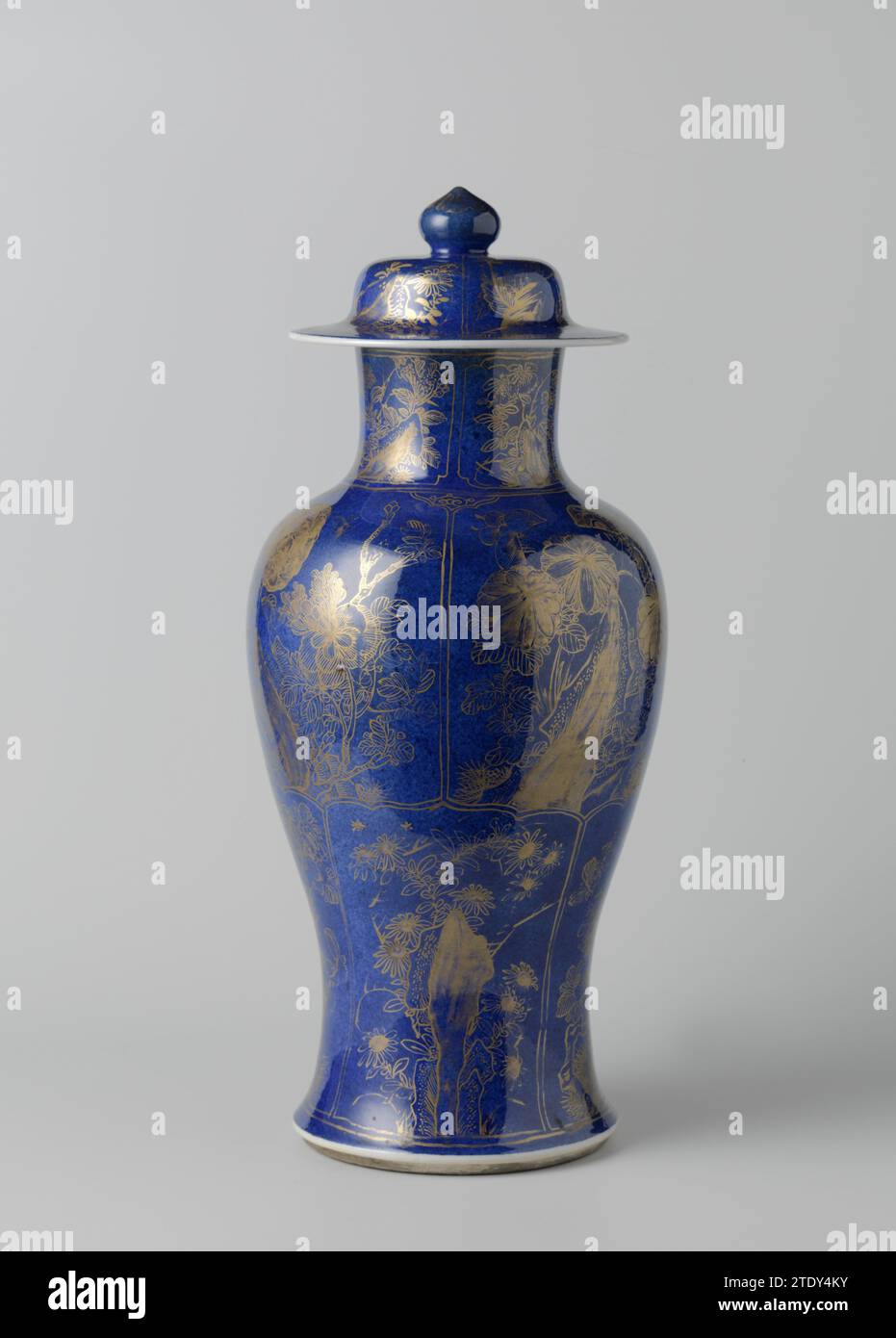 Vase couvert avec des plantes à fleurs bleu poudre dans des panneaux, anonyme, c. 1700 - c. 1724 vase à couvercle en forme de balus en porcelaine, recouvert de bleu glacé sous-jacent et peint sur le glaçage en or. L'extérieur et le couvercle du vase sont recouverts de poudré bleu (bleu poudré). L'abdomen est divisé en huit parcours festonnés avec une plante à fleurs dans une roche (pivoine, chrysanthème, aster, lotus, prunus). Un motif Ruyi entre les parcours sur l'épaule. Le cou et le couvercle également avec des plantes à fleurs en cartouches. Couvercle vase fait partie d'un ensemble de placard. Bleu poudré avec or. Porcelaine de Chine. glaçage. cobalt Banque D'Images