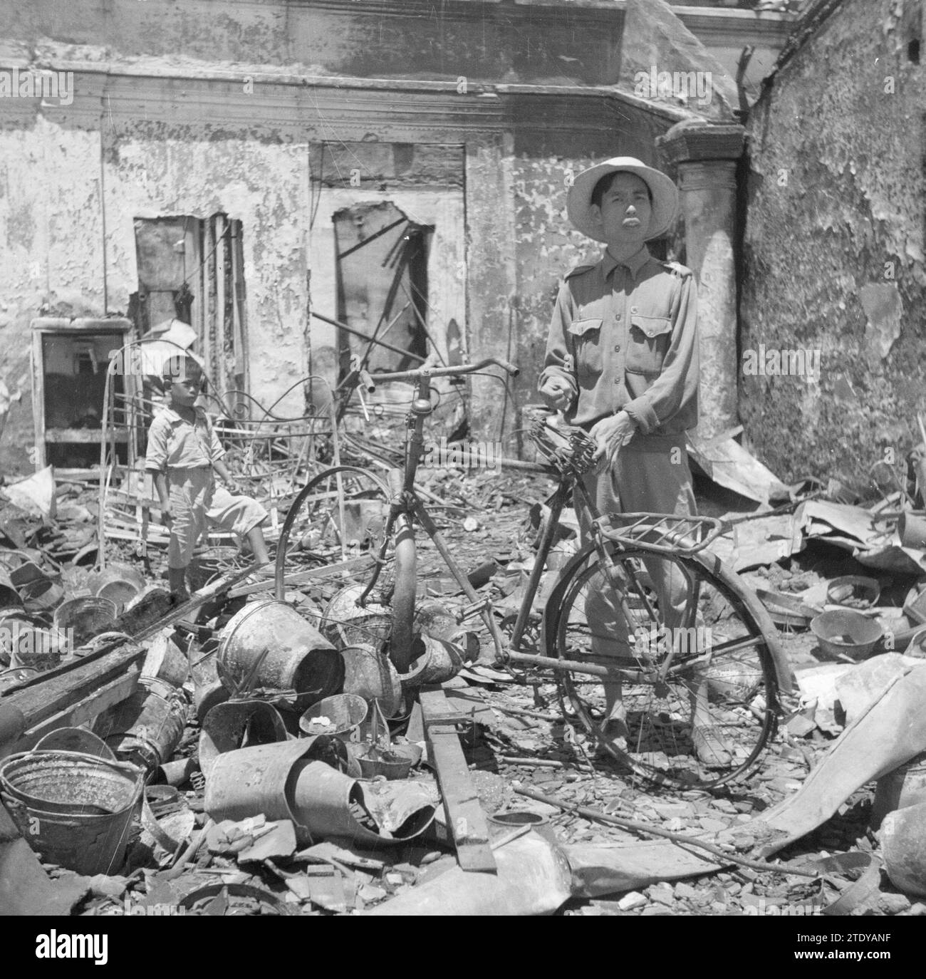 Un indonésien avec un vélo dans une ruine d'un magasin à Bandoeng ca. Mars 1946 Banque D'Images