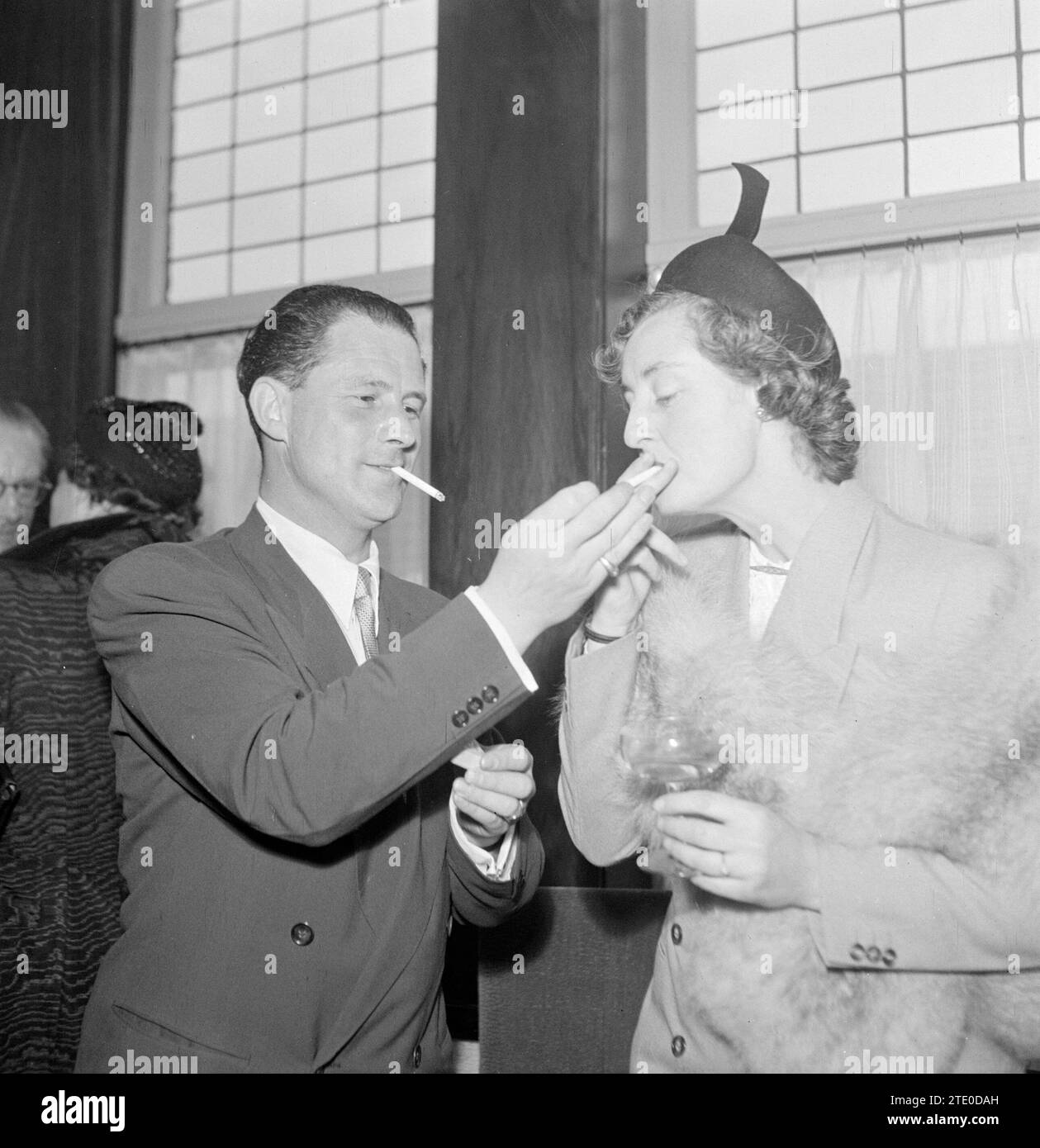 Fumer l'homme donne à la femme une lumière ca. 1950 Banque D'Images
