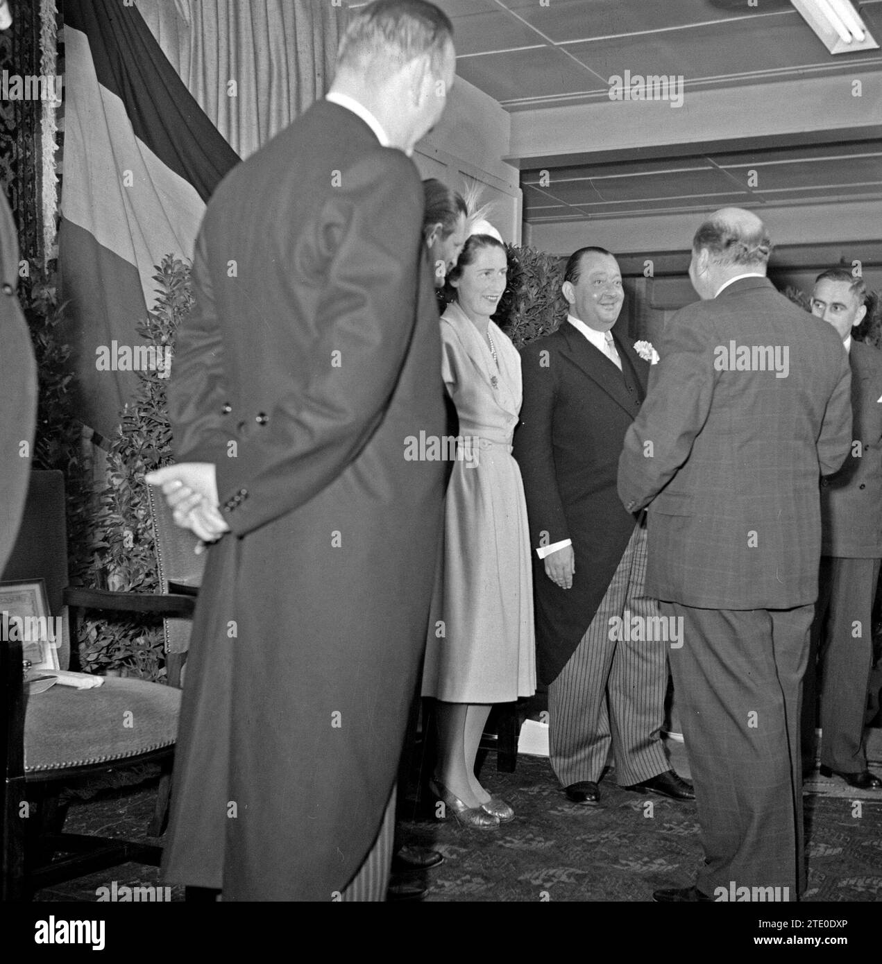 Les invités félicitent les directeurs d'usine Jan van Abbe (centre avec corsage), Albert van Abbe (centre gauche, seule la tête visible) et une femme (probablement épouse de Jan ou Albert) ca. 1950 Banque D'Images