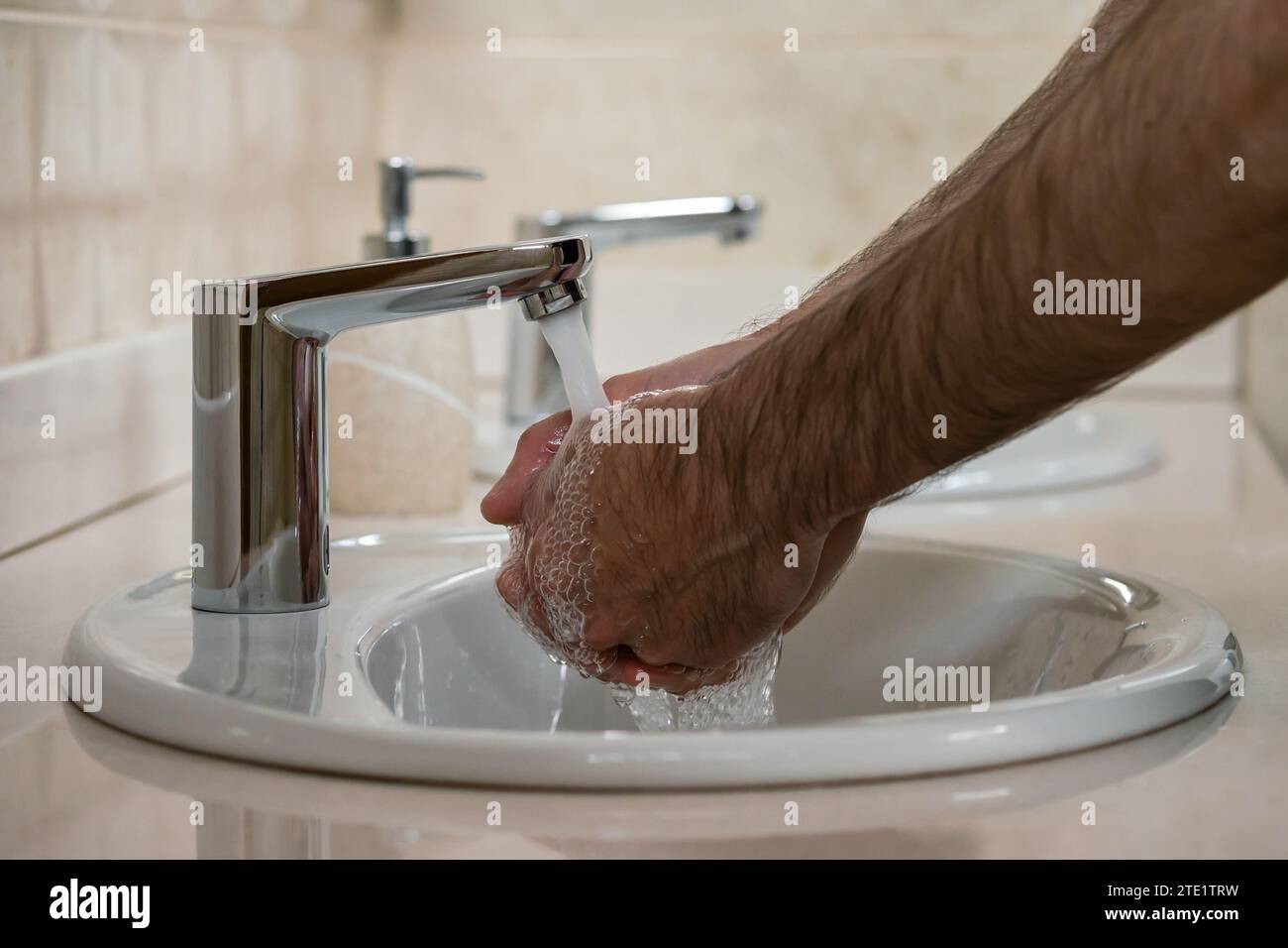 Mains d'un homme se lavant les mains sous l'eau courante d'un robinet Banque D'Images