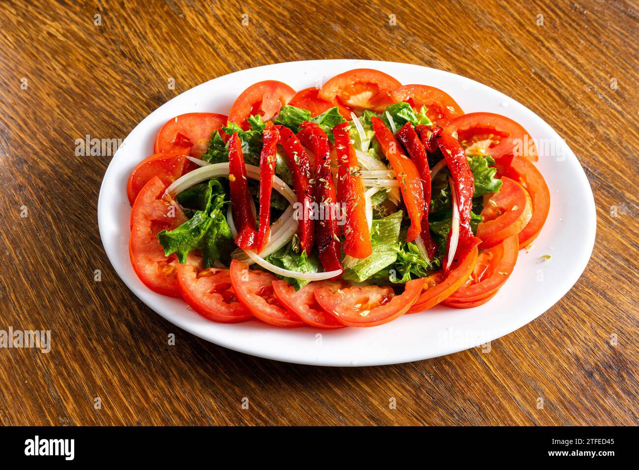 Salade fraîche avec laitue, tomates, oignons et poivrons rouges rôtis. Couleurs vives et ingrédients sains. Banque D'Images