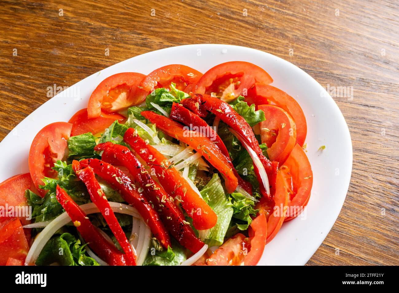 Salade fraîche avec laitue, tomates, oignons et poivrons rouges rôtis. Couleurs vives et ingrédients sains. Banque D'Images