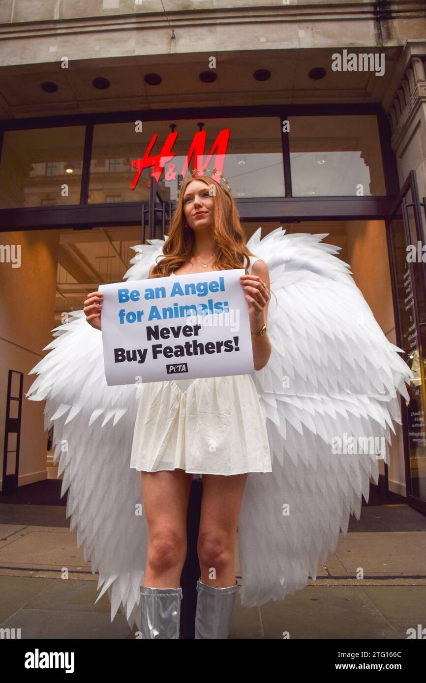 Londres, Royaume-Uni. 20 décembre 2023. Un activiste PETA (People for the Ethical Treatment of Animals) habillé en ange se tient devant le magasin H&M sur Regent Street avec une pancarte exhortant les gens à ne pas acheter de produits contenant des plumes. Le groupe de défense des droits des animaux affirme que ses enquêtes ont mis en lumière la cruauté envers les oiseaux dans les entreprises fournissant des plumes pour les vêtements en duvet et d'autres articles dans des magasins comme H&M. Crédit : SOPA Images Limited/Alamy Live News Banque D'Images