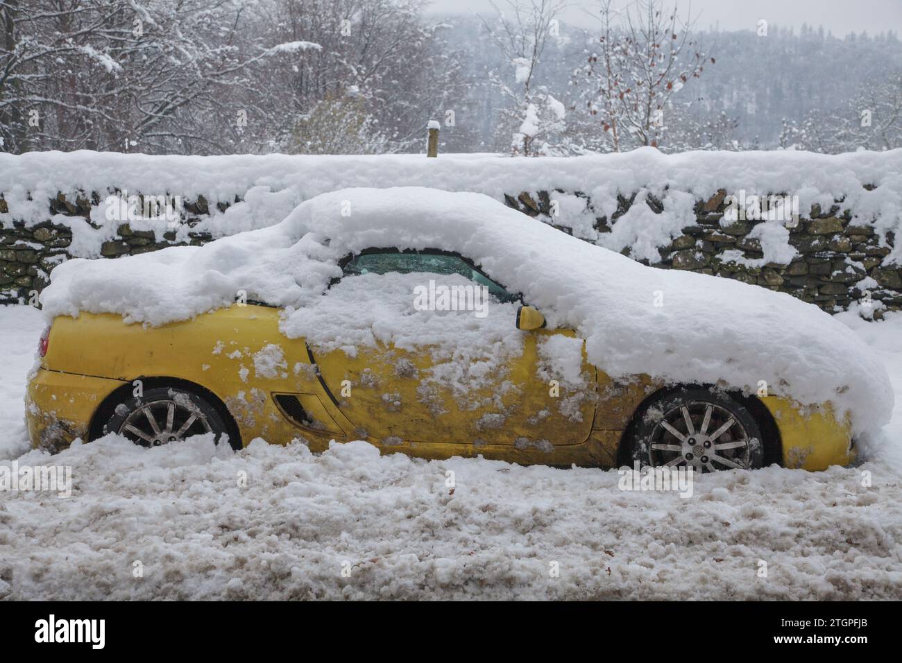 Une voiture jaune abandonnée par la route après de fortes chutes de neige près de Windermere dans la région des lacs anglais Banque D'Images
