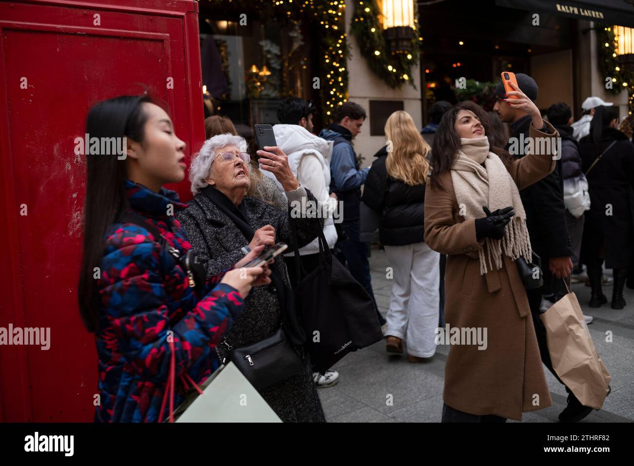 Touristes festifs en force prenant des selfies et des photos d'expositions de Noël le long de Old Bond Street au cœur de Mayfair à Londres, le 20 décembre 2023. Banque D'Images