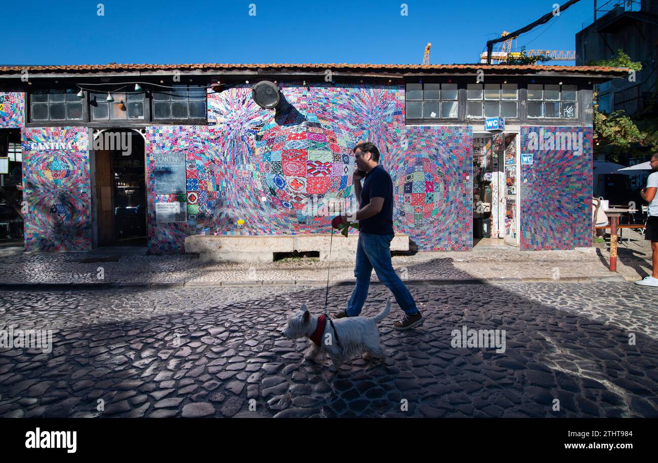 Usine LX, Lisbonne, Portugal. Street art à l'extérieur de la Cantina LX. Un homme promène son chien devant l'oxymore Tiling de l'artiste portugaise, abstraite géométrique et cinétique Margarida Sardinha. Banque D'Images