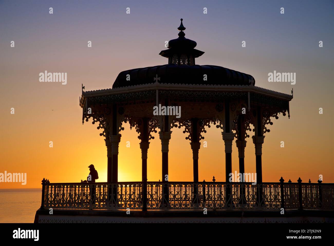 Silhouette du kiosque victorien de Brighton avec un homme solitaire au coucher du soleil. Brighton & Hove, Sussex de l'est, Angleterre. Ciel bleu et doré. Banque D'Images