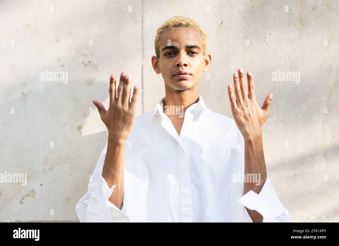 Portrait d'un jeune homme noir blond posant avec les mains levées, paumes retournées, espace de copie Banque D'Images