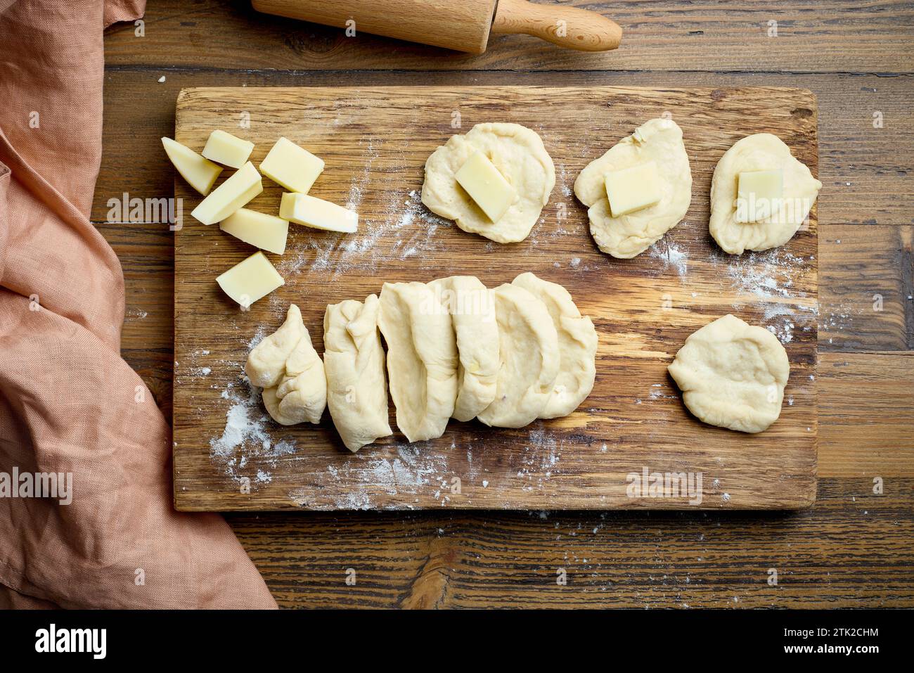 petits pains à pain à pâte de levure crue remplis de fromage sur la table de cuisine en bois, vue de dessus Banque D'Images