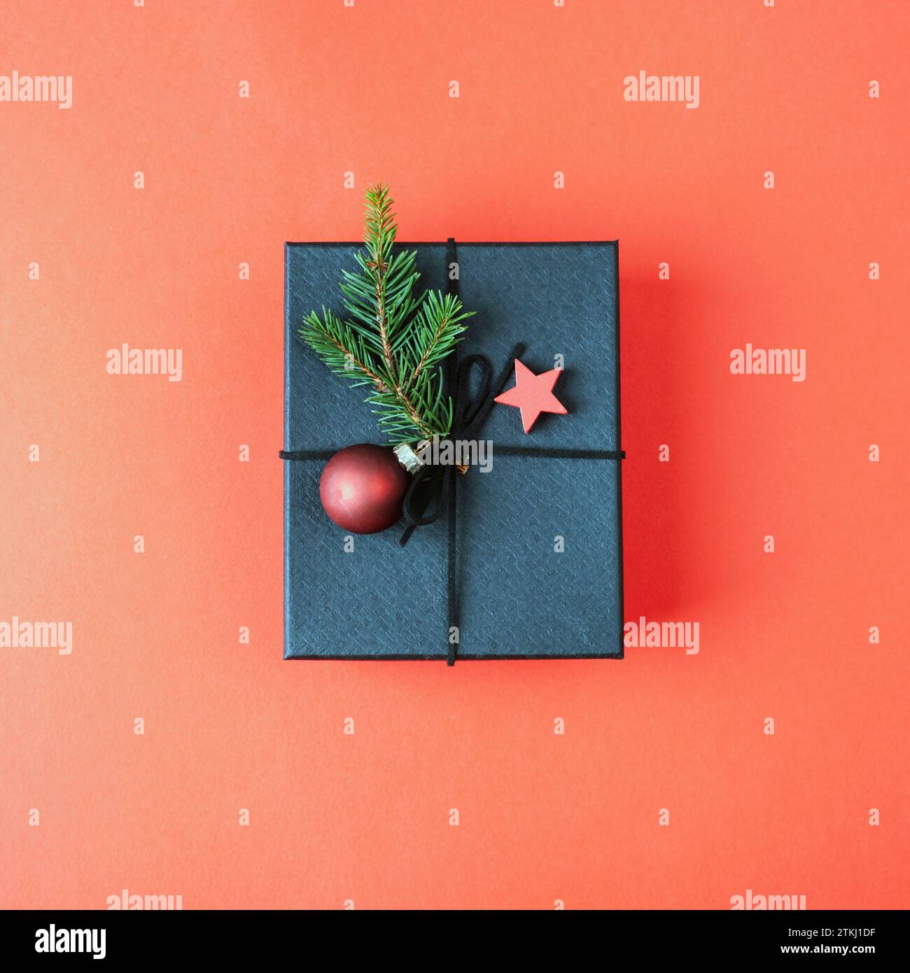 Boîte cadeau noire avec décorations de Noël sur fond rouge. Vue de dessus, pose à plat. Banque D'Images