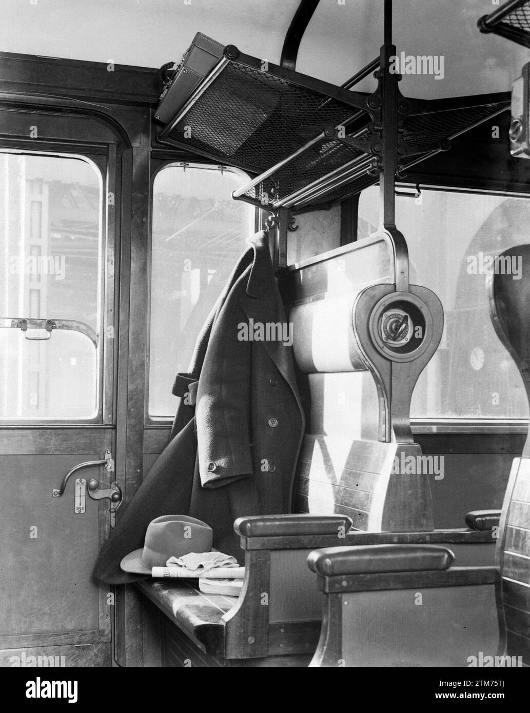 Intérieur d'un compartiment de train : manteau suspendu, chapeau, porte-bagages et bancs ca. 1932 Banque D'Images