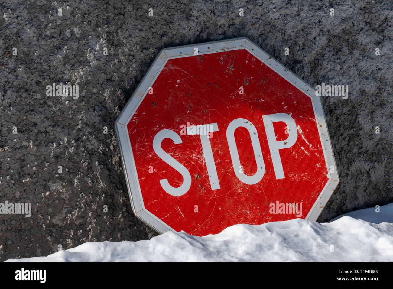 Stop , panneau de signalisation contre fond de mur de béton. Sol recouvert de neige. Couleurs rouge et blanc. Informations. Banque D'Images