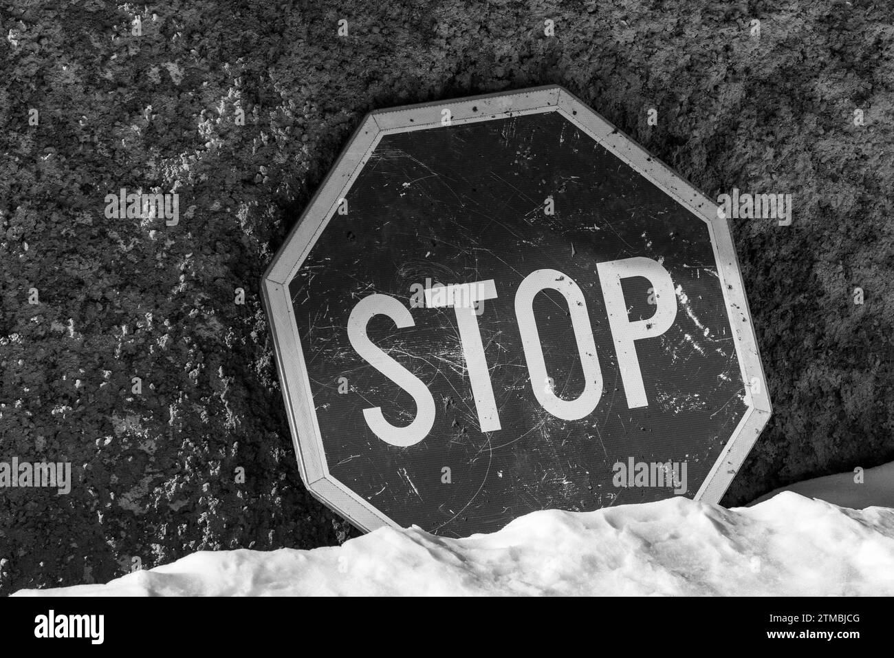 Stop , panneau de signalisation contre fond de mur de béton. Sol couvert de neige.couleurs noir et blanc. Informations. Monochrome. Banque D'Images