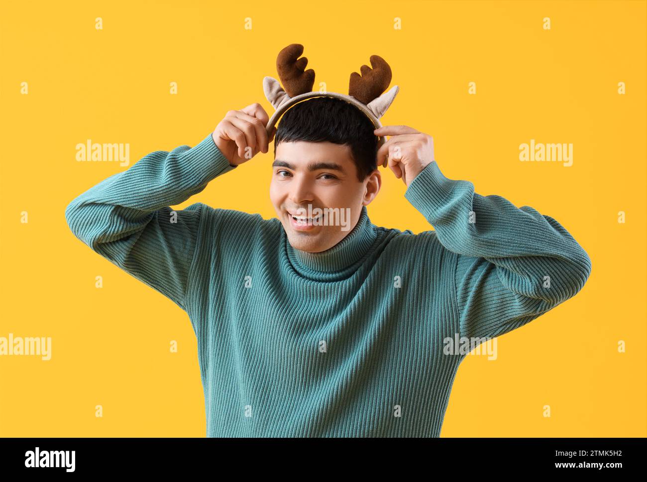 Jeune homme dans les cornes de cerf de Noël sur fond jaune Banque D'Images