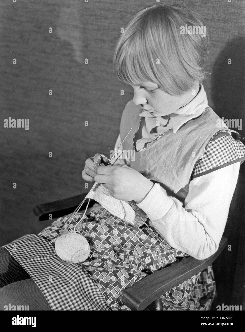 Jeune fille assise sur une chaise tricotant ca. 1932 Banque D'Images