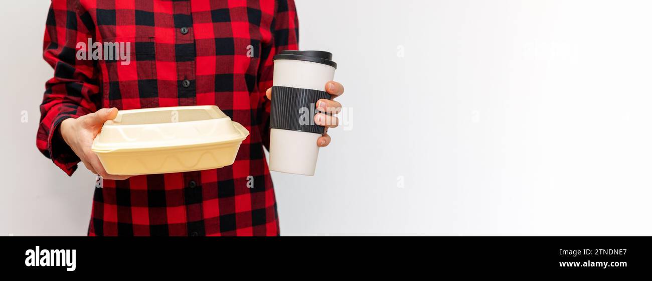Personne féminine tenant la tasse de café de voyage et la boîte à lunch dans ses mains devant le fond Uni avec l'espace de copie. Banque D'Images