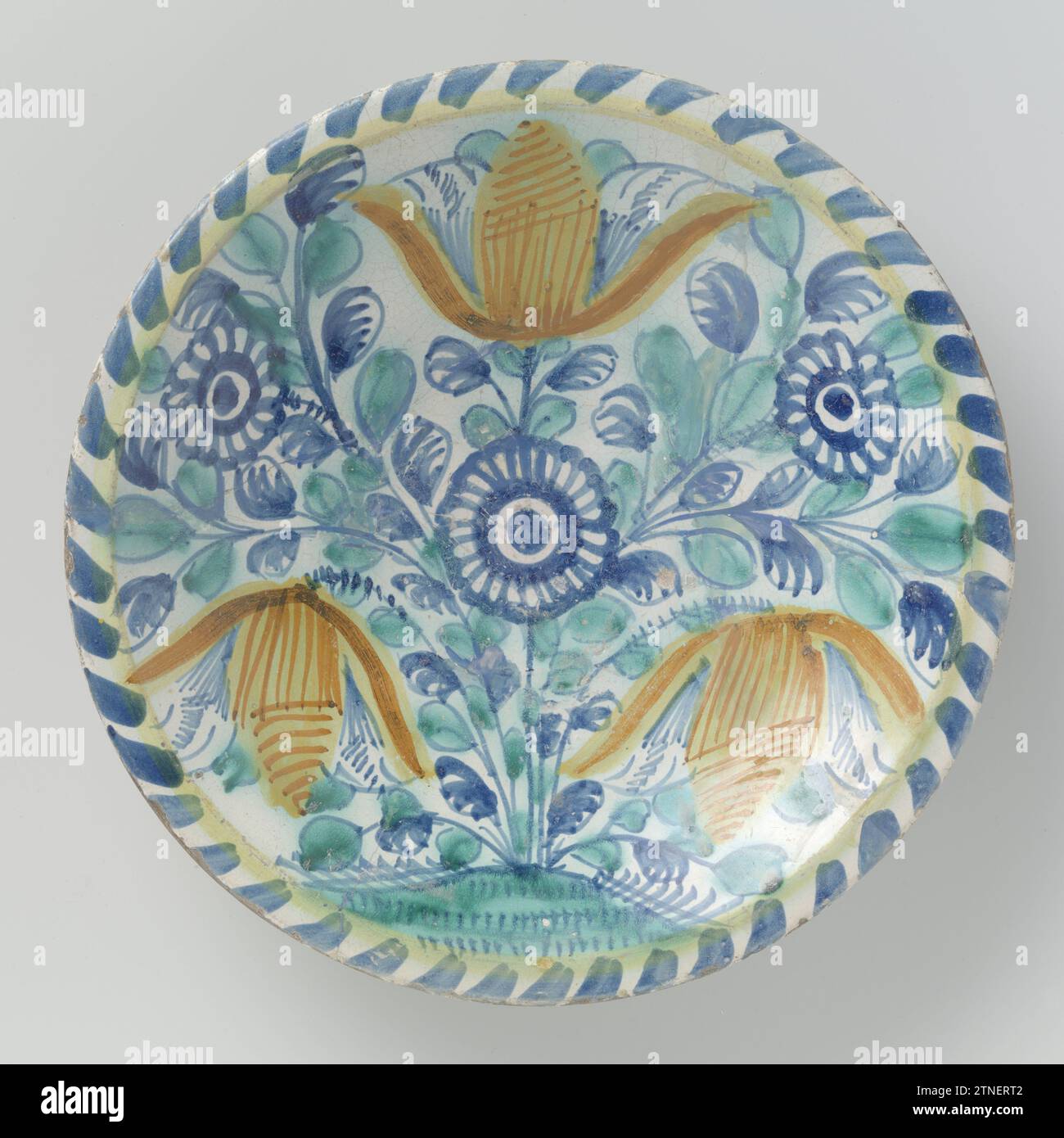 Plat, peint avec tulipes et asters (?), Anonyme, c. 1660 plat rond de majolique peinte multicolore. Le plat est peint avec des fleurs stylisées (trois tulipes et trois asters?) Sur un sol. Deux tulipes laissent pendre leur tête. Les légumes (tirets bleus) sont peints le long du bord. Le plat a un bord de pied large et plat. Faïence londonienne. glaçure d'étain. Majolica glacé au plomb plat rond en majolica peint multicolore. Le plat est peint avec des fleurs stylisées (trois tulipes et trois asters?) Sur un sol. Deux tulipes laissent pendre leur tête. Les légumes (tirets bleus) sont peints le long du bord. Le plat a un large Banque D'Images