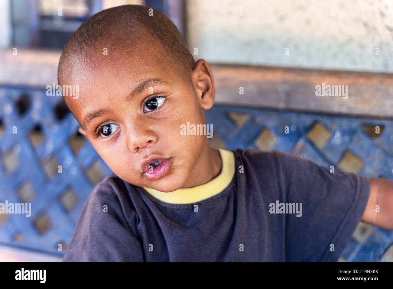 enfant africain assis sur un banc devant la maison Banque D'Images