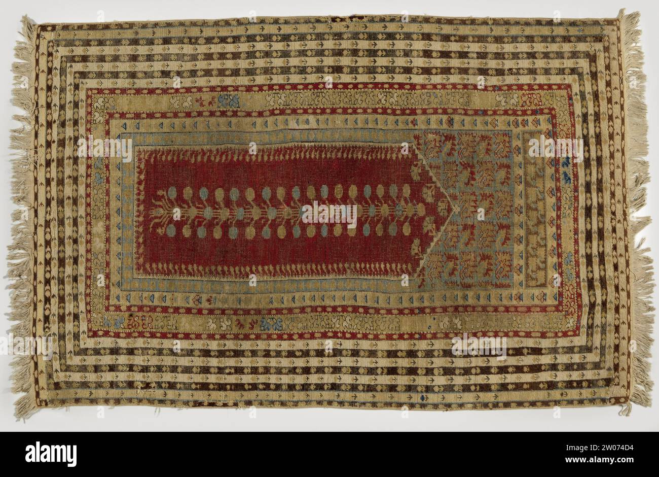 Tapis BID avec un panneau transversal, Kula ,, 1800 - 1900 tapis de prière avec un panneau transversal, Kula. Milieu de terrain : Mihrab rouge avec façade triangulaire plate, dans laquelle une tige de fleur ramifiée pend en bleu et jaune. Les balançoires sont bleu ciel avec des rangées droites d'Anjelieren. Un panneau supérieur étroit est en brun avec Anjelieren. Arêtes : multiples. Le plus large se compose de sept lignes en blanc, violet, noir et beige. Le premier zoom intérieur est blanc, le deuxième jaune pâle et est gagné en tuyauterie. À l'extérieur, ne court qu'un seul tuyau de ce type. Soin laine tapis de prière avec un panneau transversal, Kula. Milieu de terrain : Mihrab rouge avec triangle plat Banque D'Images