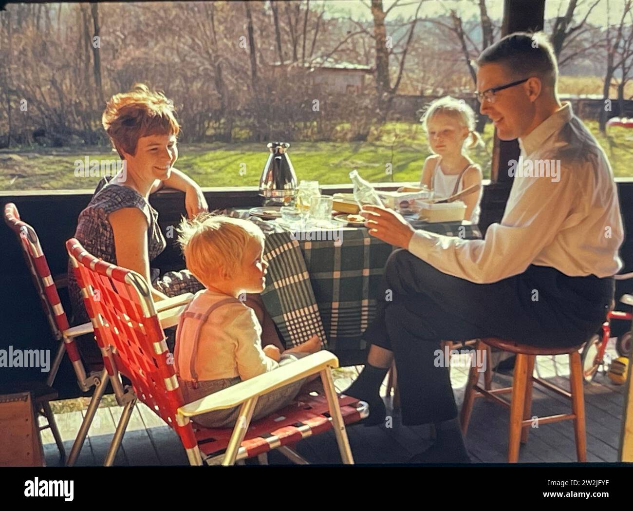 Une jeune famille de quatre personnes dans les années 1960 profite d'un repas sur la terrasse de leur chalet à l'extérieur de Stockholm, en Suède. Banque D'Images