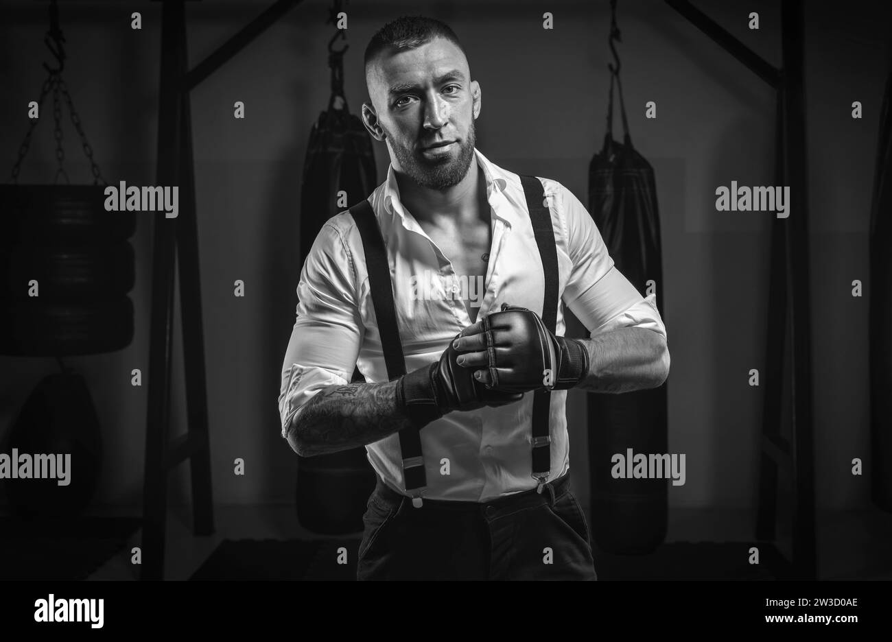 Image d'un homme brutal dans une chemise blanche et des bretelles debout sur le fond d'une salle de boxe. Arts martiaux mixtes Le concept de poing Banque D'Images
