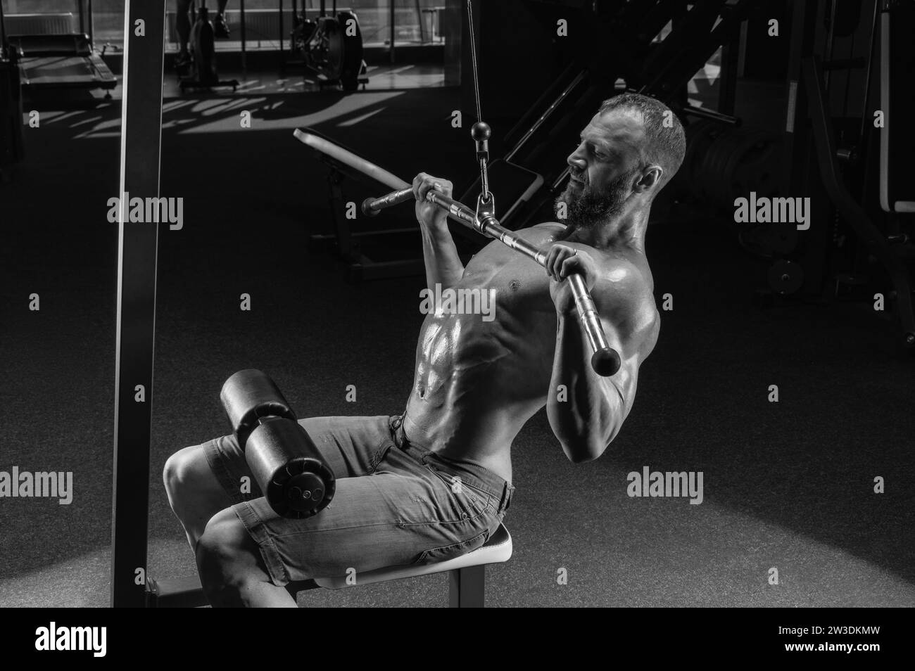 Athlète professionnel effectue un exercice dans la salle de gym. Tire la barre vers sa poitrine. Exercice pour pomper le dos. Supports mixtes Banque D'Images