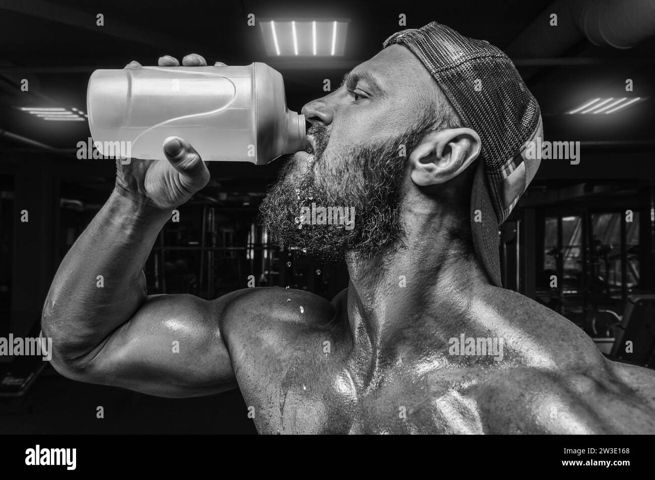 Homme musclé dans la salle de gym buvant dans un shaker. Concept de fitness et de musculation. Supports mixtes Banque D'Images