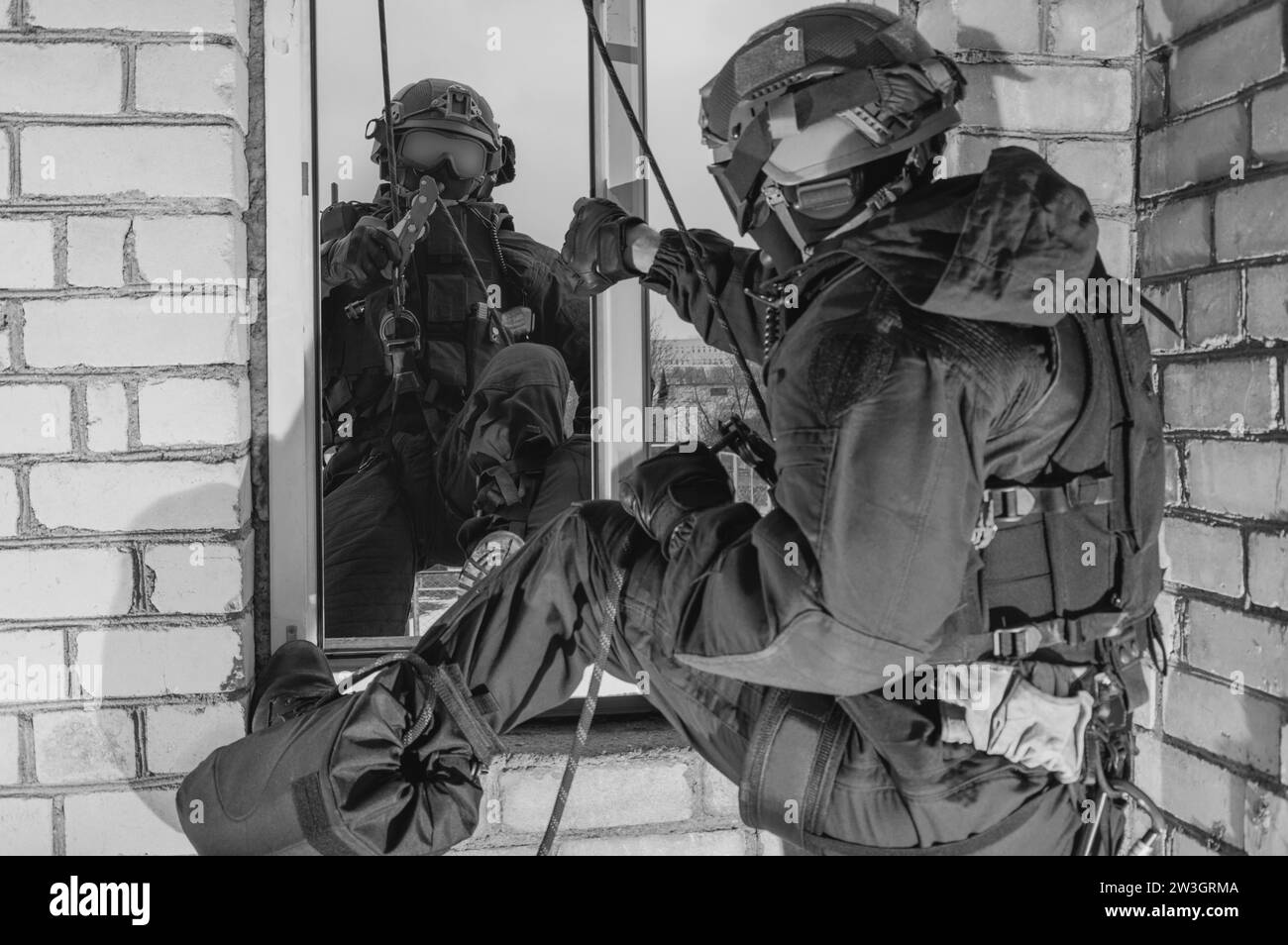 Un groupe de combattants des forces spéciales prennent d'assaut le bâtiment par la fenêtre. Sessions de formation de l'équipe SWAT. Concept anti-terroriste. Grimpeurs. Supports mixtes Banque D'Images