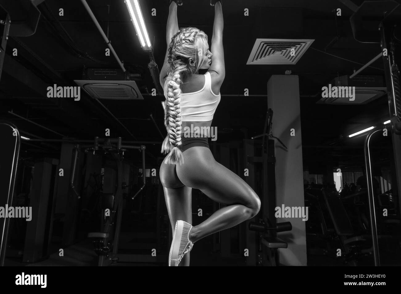 Jolie fille busty se tire sur le bar. Concept de fitness et de musculation. Supports mixtes Banque D'Images