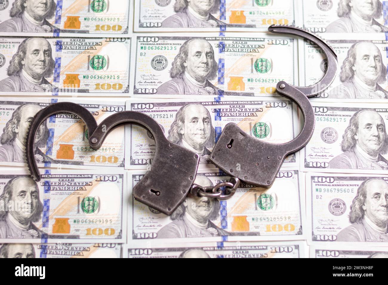Menottes sur le fond de billets de cent dollars. Commerce illégal. Concept de justice. Supports mixtes Banque D'Images