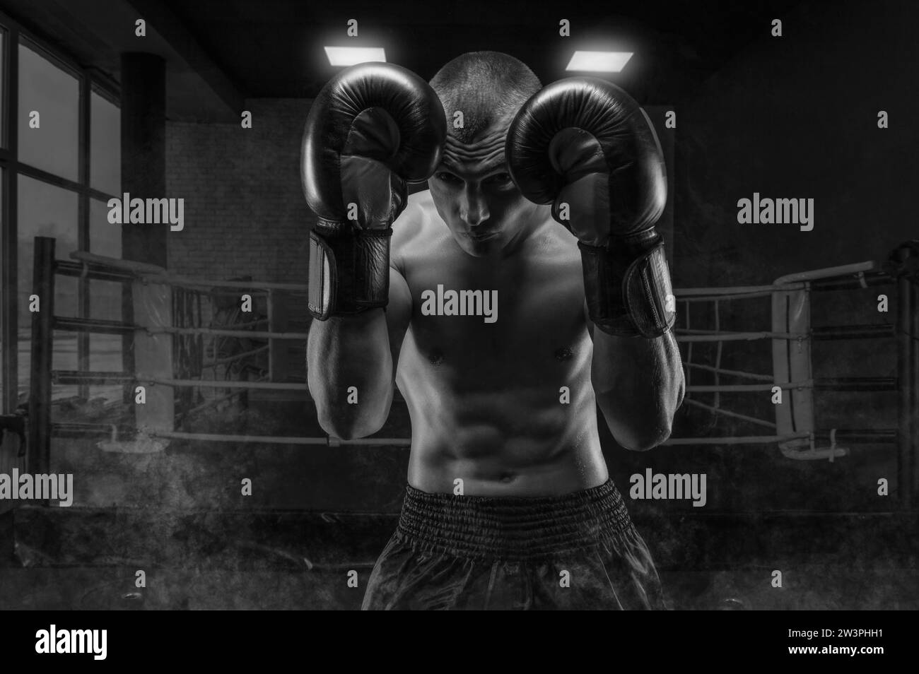 Image d'un boxeur dans la salle de gym. Il se couvre la tête avec des gants. Rack de protection. Arts martiaux mixtes Concept sportif Banque D'Images