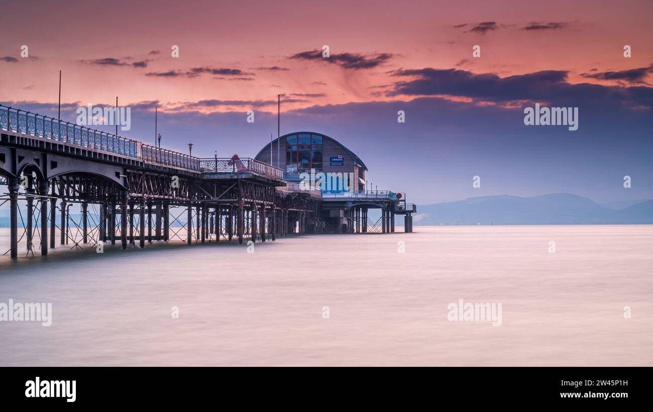 La longue jetée dans les Mumbles, Swansea, au sud du pays de Galles. La structure en bois et en acier se trouve dans une mer calme, avec un ciel rouge derrière elle, au lever du soleil Banque D'Images