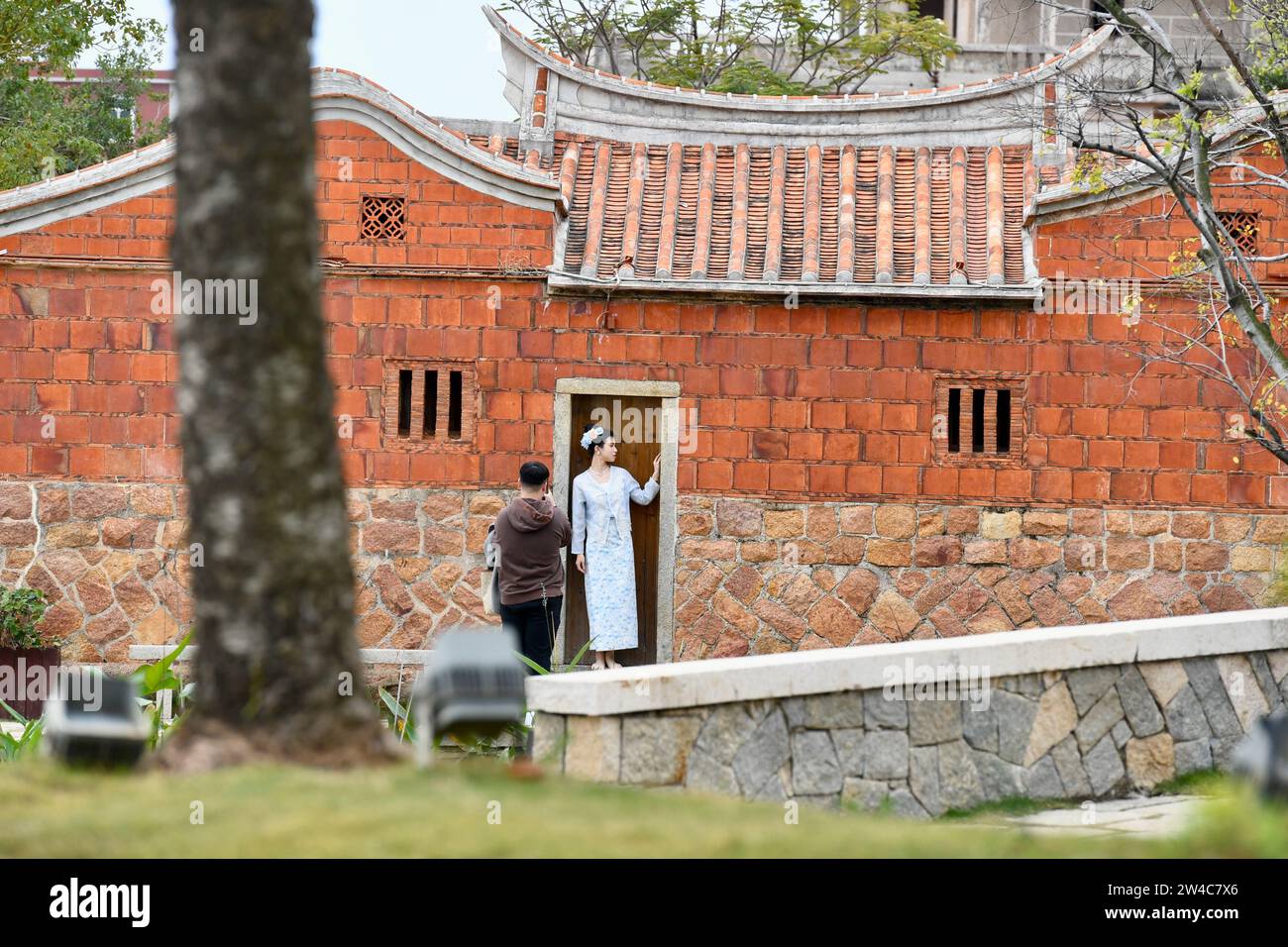 JINJIANG, 21 déc. 2023 (Xinhua) -- des touristes prennent des photos dans un bâtiment Minnan en briques rouges dans le village de Wulin de Jinjiang, dans la province du Fujian, dans le sud-est de la Chine, le 19 décembre 2023. Dans le village de Wulin, dans la province du Fujian de l'est de la Chine, les visiteurs sont souvent fascinés par le mélange de styles architecturaux : maisons locales en briques rouges, bâtiments gothiques, structures gréco-romanes et bâtiments mêlant éléments chinois et occidentaux. Le mélange éclectique de styles architecturaux raconte de façon vivante l'histoire de la connexion du village avec la communauté chinoise d'outre-mer. Fin 19e et début 20e cen Banque D'Images