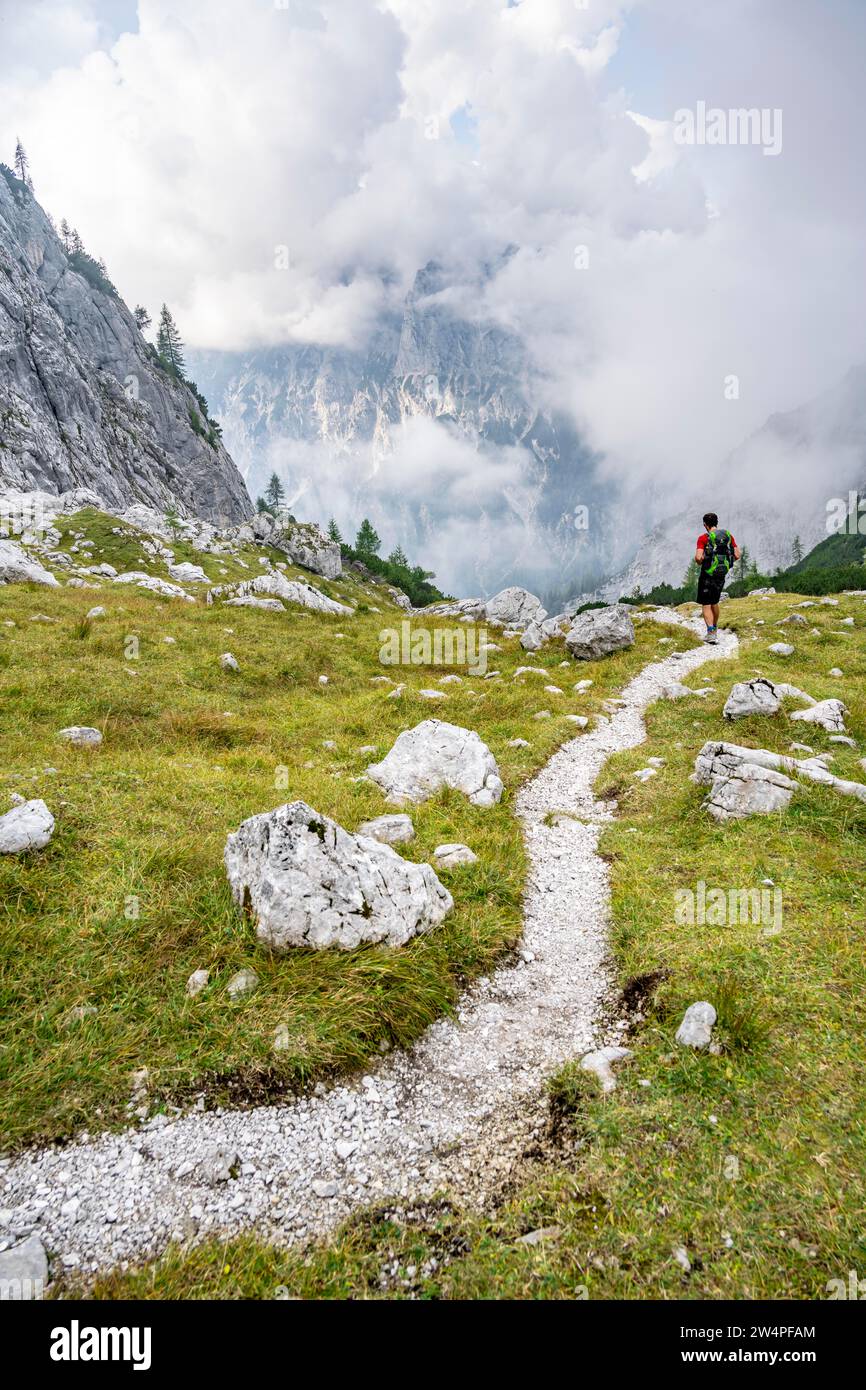 Alpiniste sur un sentier de randonnée, montagnes nuageuses, descente sur l'Ofental, tour de montagne sur le Hochkalter, traversée de Hochkalter, Alpes de Berchtesgaden Banque D'Images