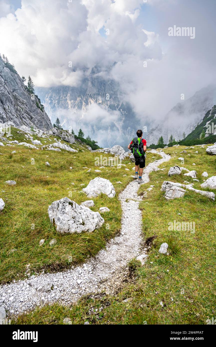 Alpiniste sur un sentier de randonnée, montagnes nuageuses, descente sur l'Ofental, tour de montagne sur le Hochkalter, traversée de Hochkalter, Alpes de Berchtesgaden Banque D'Images