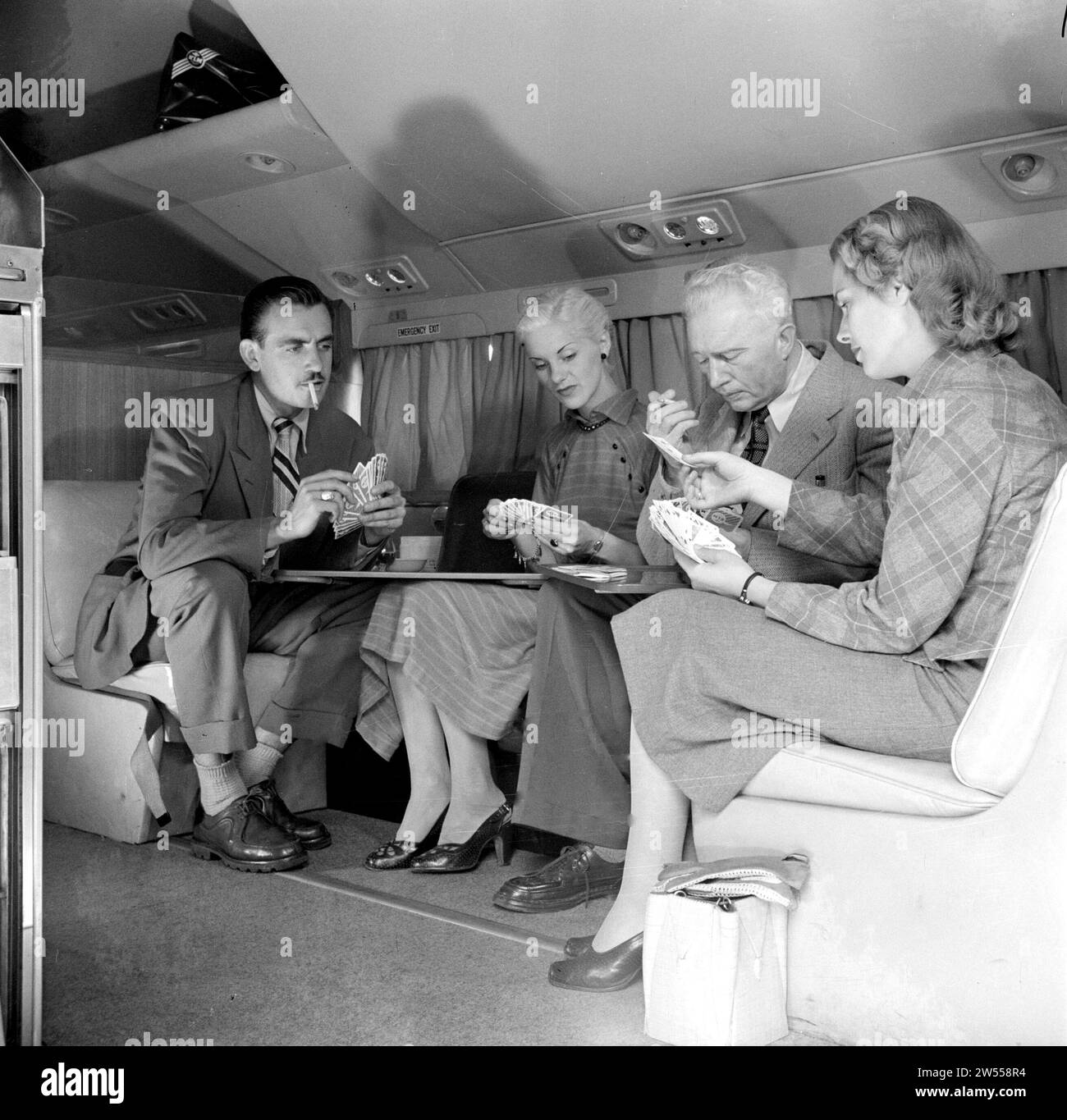 Les voyageurs se détendent à bord d'un avion de passagers KLM avec un jeu de cartes ca. 1950 Banque D'Images