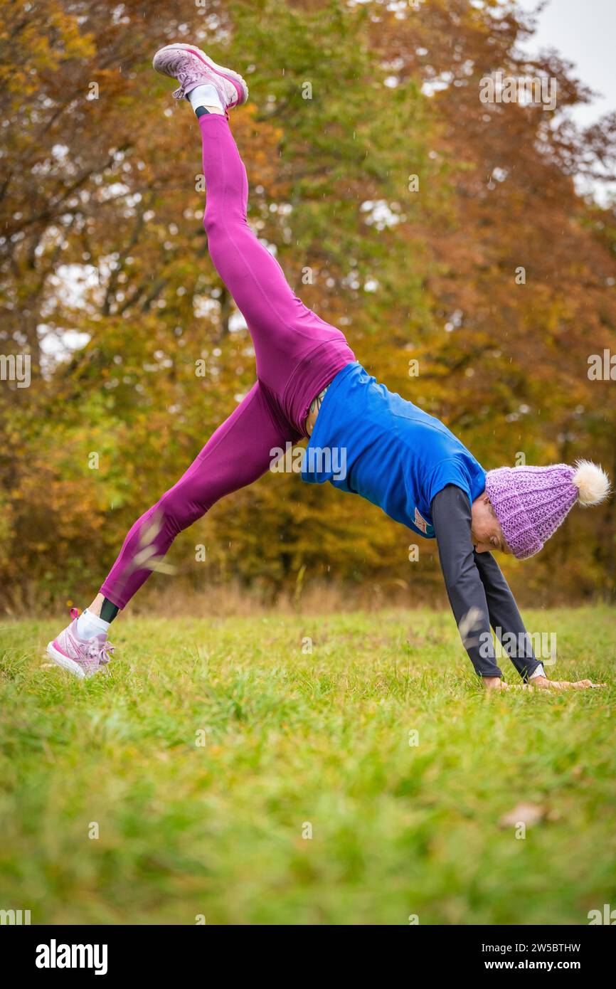 Femme passionnée de fitness pratiquant handstand à l'extérieur, entourée de couleurs d'automne, Gechingen, Forêt Noire, Allemagne Banque D'Images