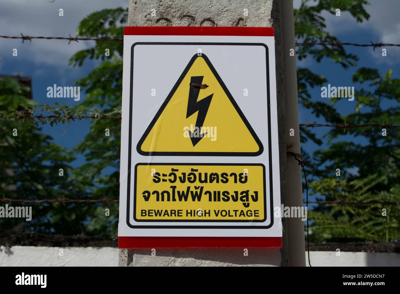 attention signe de haute tension, écrit en thaï et en anglais, avec symbole d'avertissement, à phetchabun, thaïlande Banque D'Images