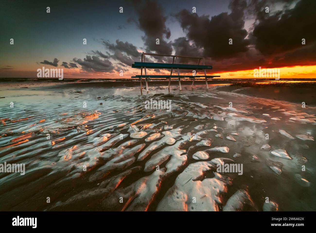 Silhouette d'un banc sur une plage inondée après une tempête au coucher du soleil, Parnu, Estonie Banque D'Images