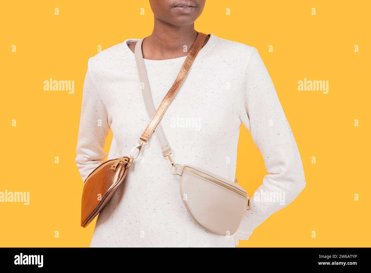 Crop anonyme mince femme afro-américaine en robe blanche avec porter sac à bandoulière tendance tout en se tenant sur fond jaune Banque D'Images