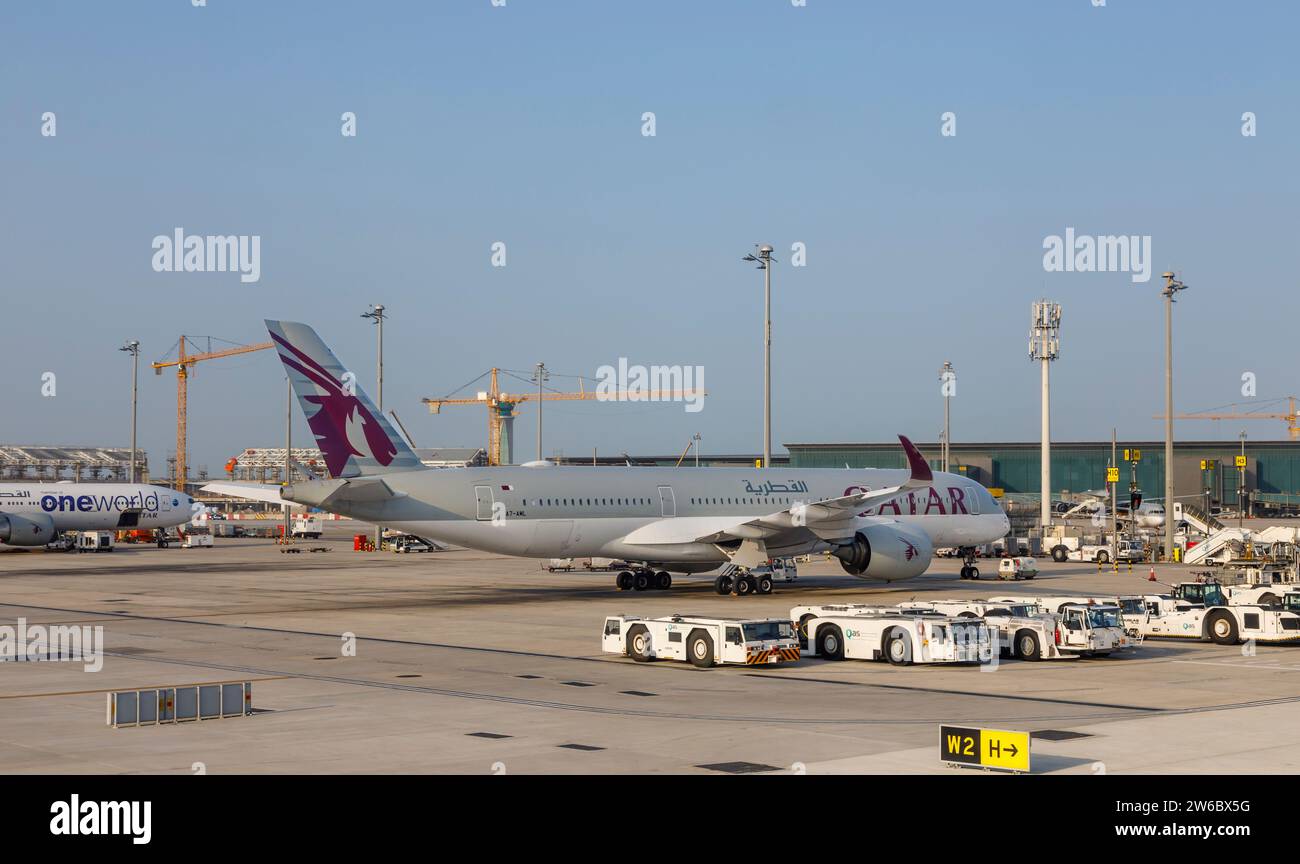 Vue latérale d'un avion Airbus A350-900 de Qatar Airways et d'un avion Douglas remorquant des tracteurs à l'aéroport international Hamad à Doha, Qatar Banque D'Images