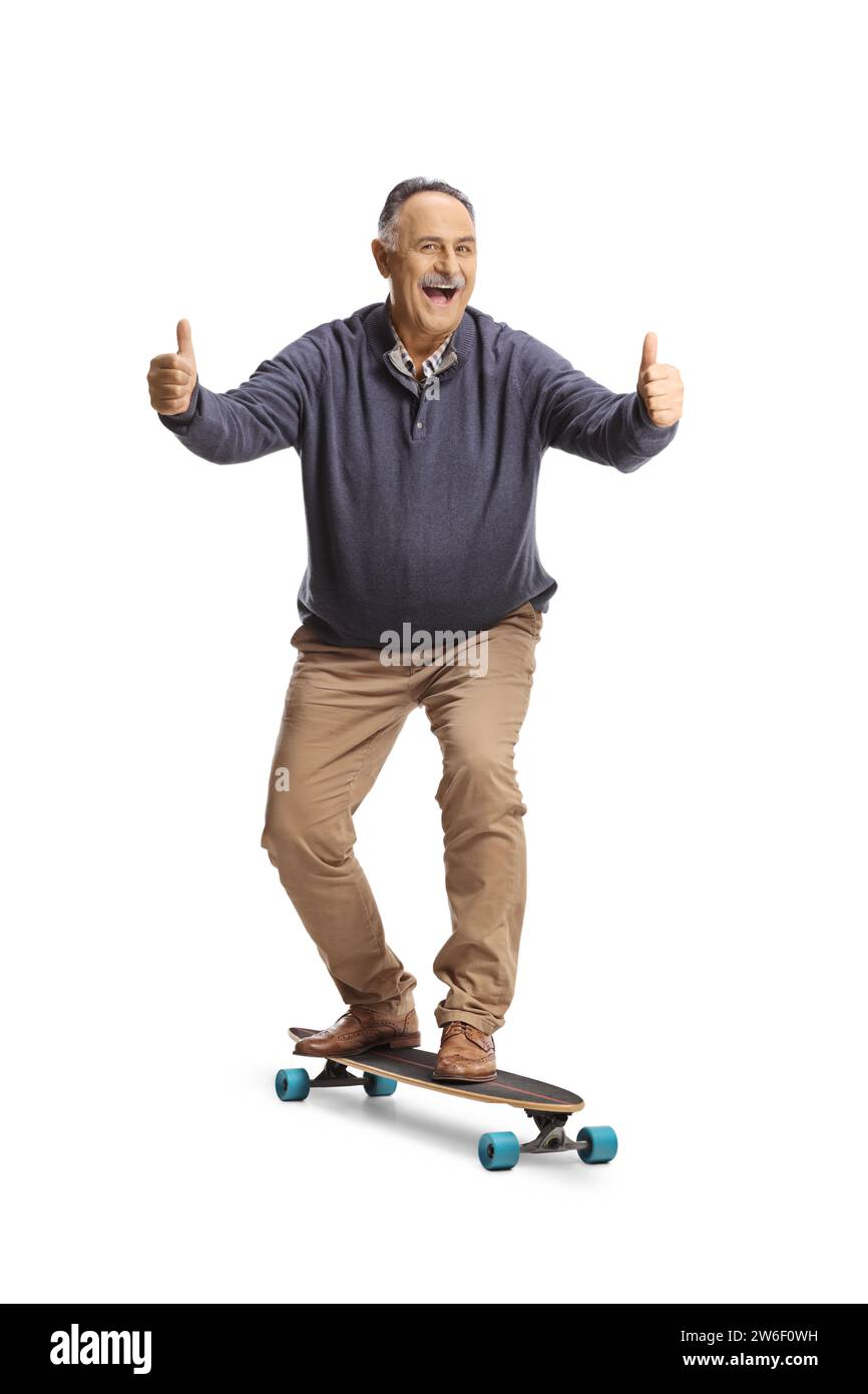 Portrait en longueur d'un homme mûr joyeux chevauchant un skateboard et faisant des gestes pouces vers le haut isolé sur fond blanc Banque D'Images