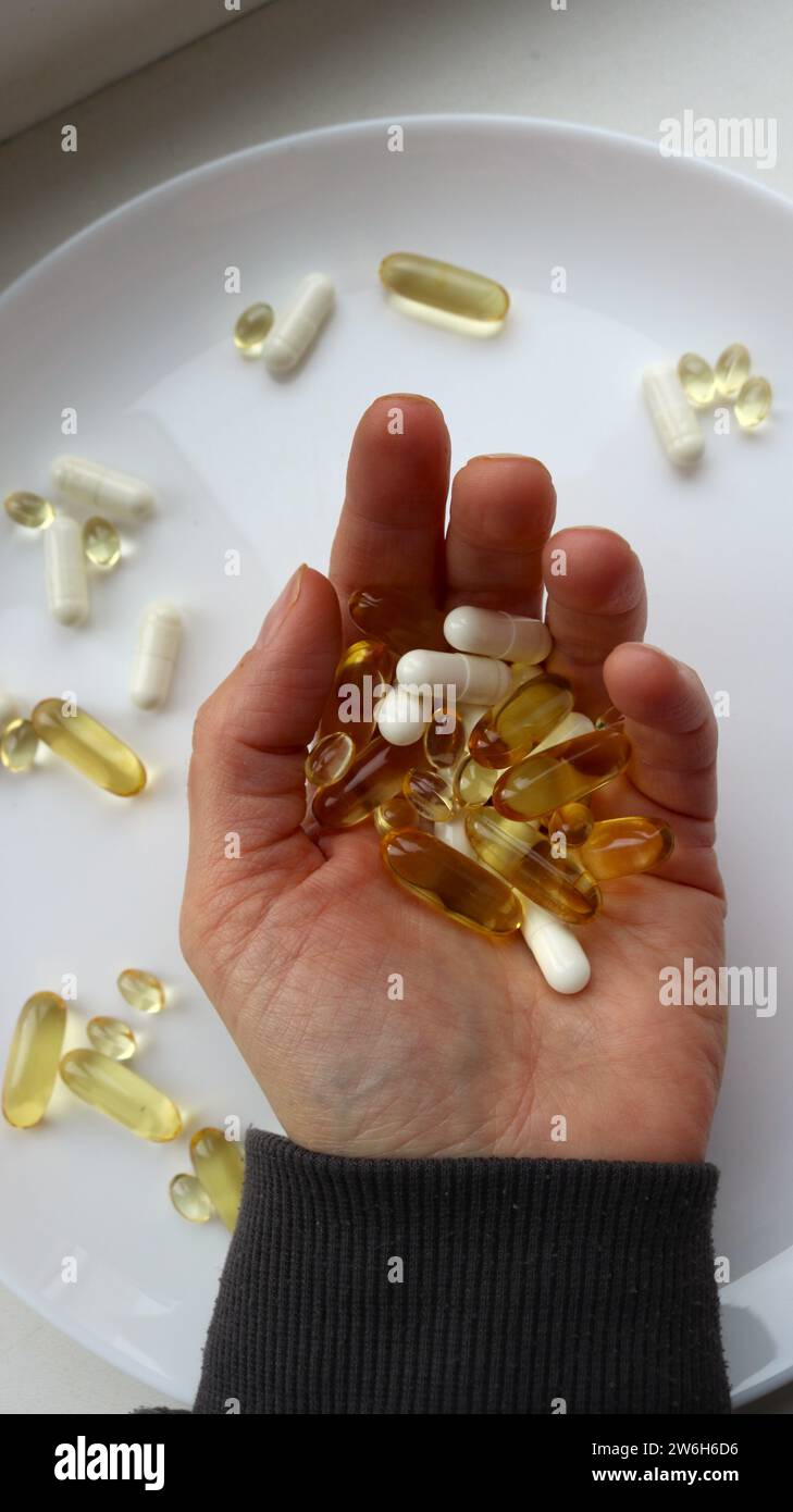 main féminine avec une poignée de vitamines et de comprimés sur la paume, image verticale, prenant des vitamines à fortes doses Banque D'Images