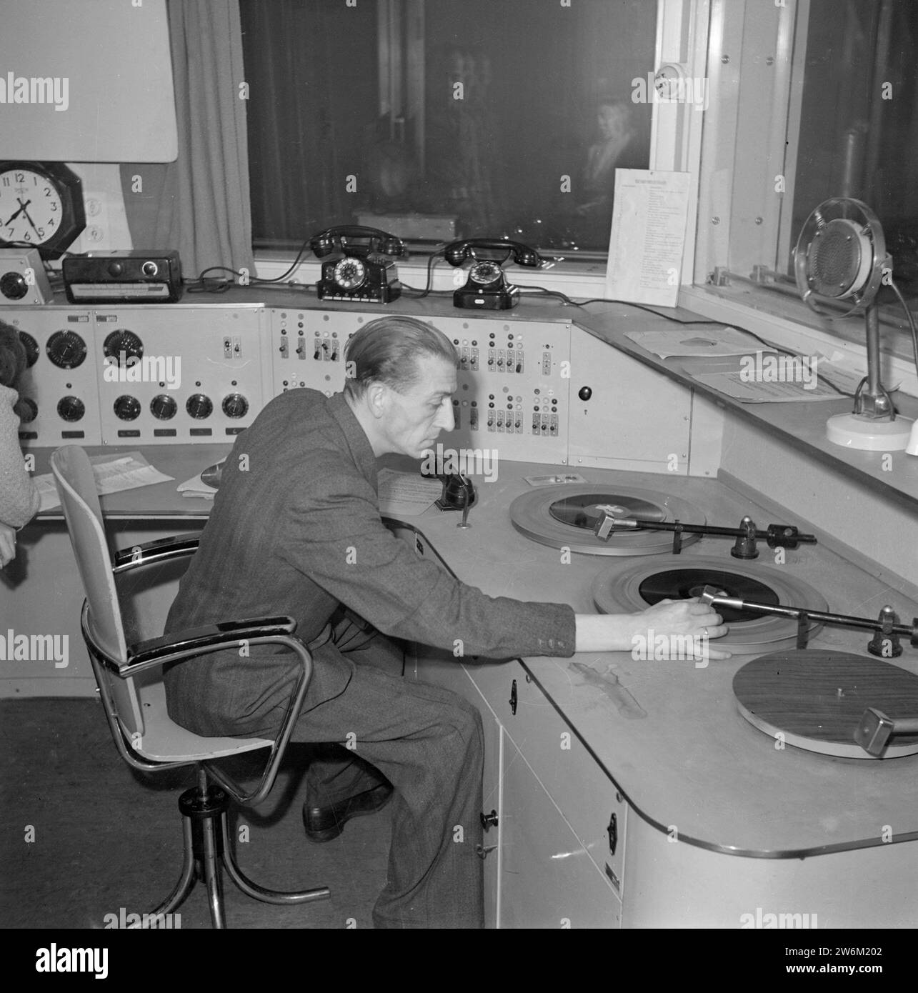 Émission de radio. L'employé d'une station de radio met sur un record de 78 tr/min ca. non daté Banque D'Images